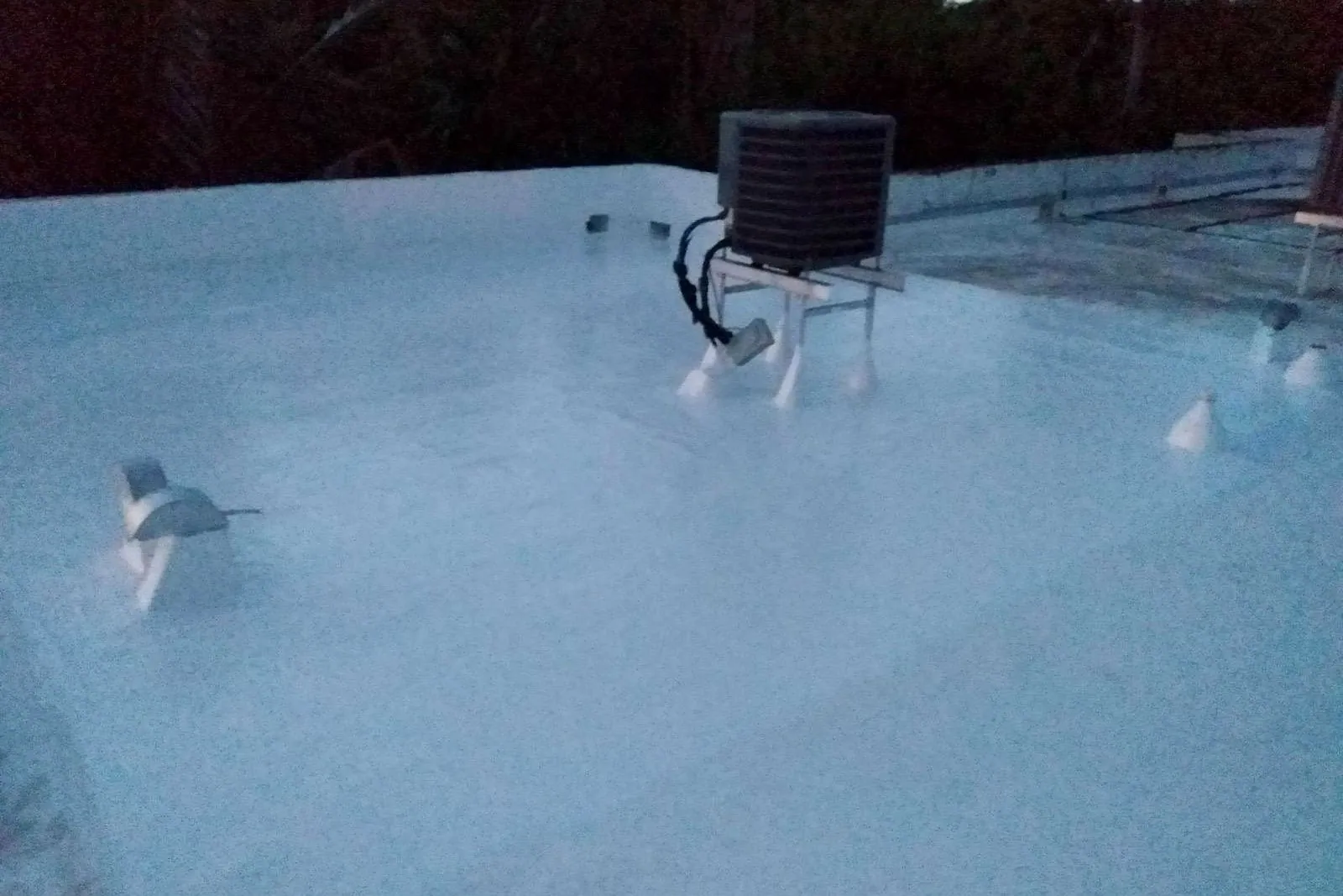 A flat townhouse roof before and after being cleaned and coated in white silicone — after