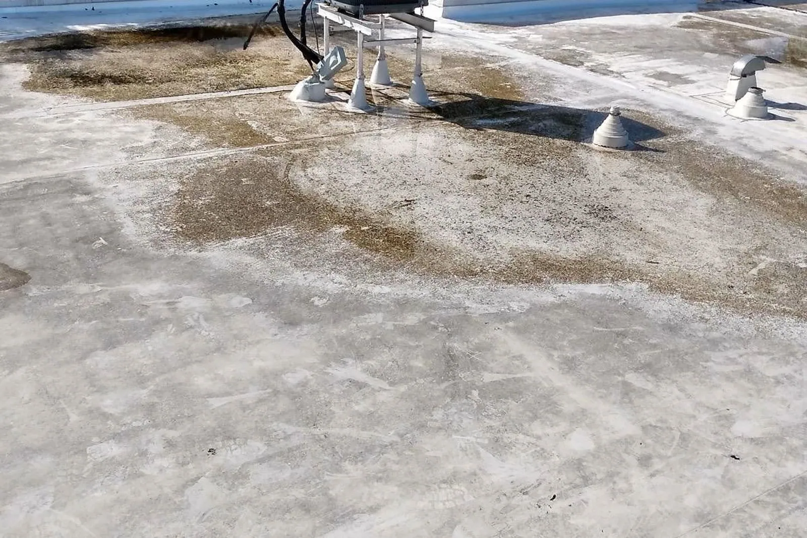 A flat townhouse roof before and after being cleaned and coated in white silicone — before