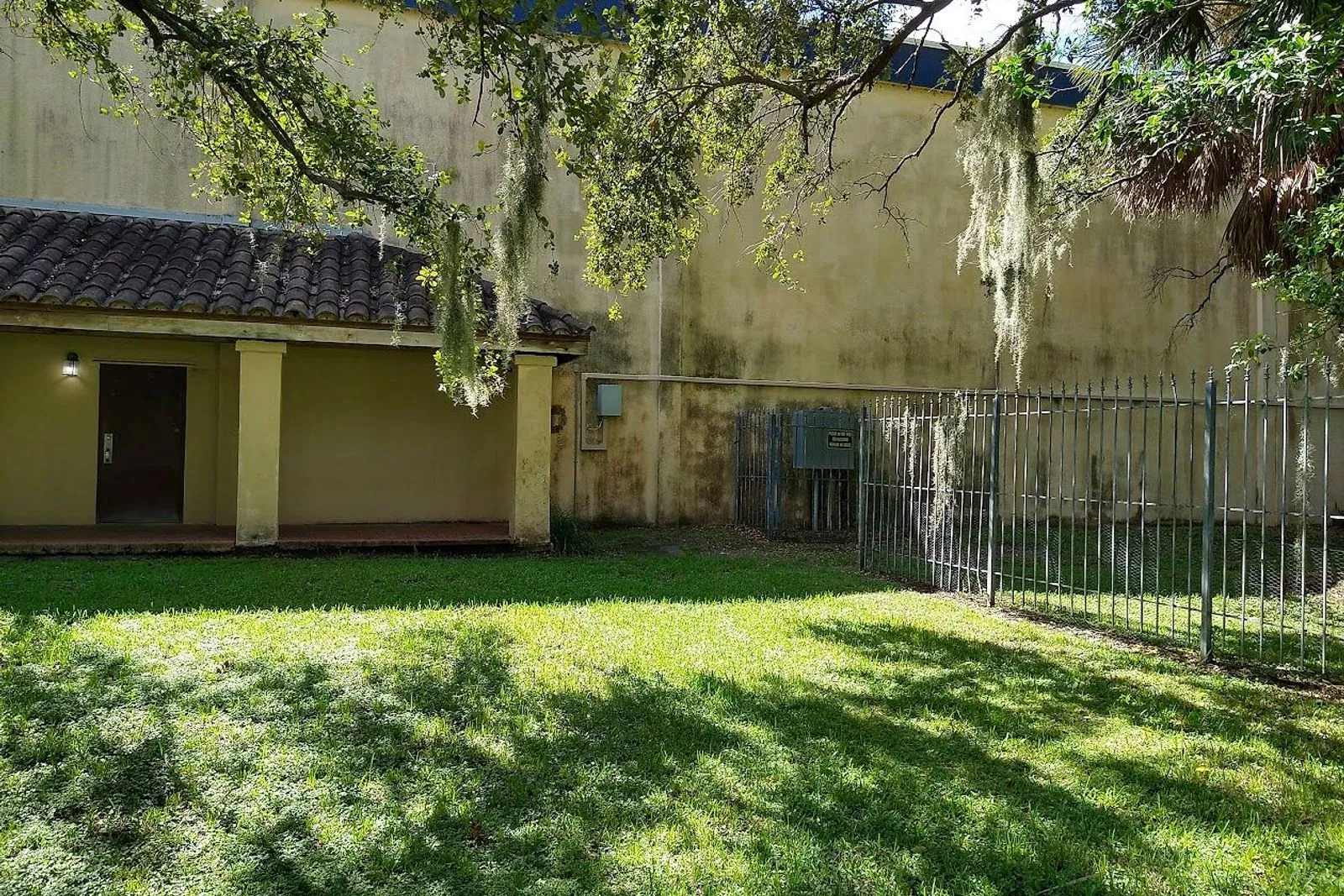 A commercial stucco building and its barrel tile roof before and after cleaning — before