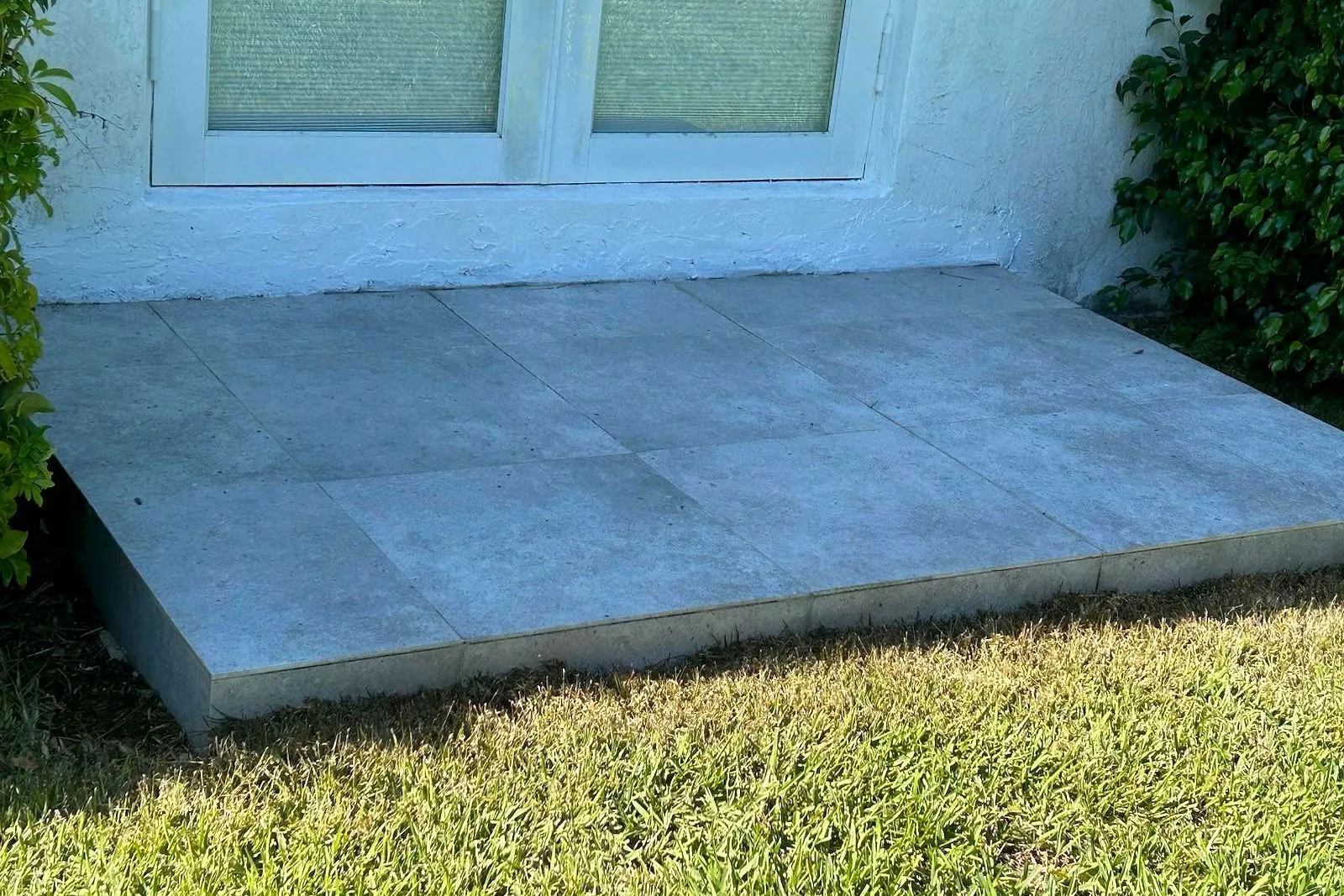 A concrete slab stained orange by sprinkler rust, before and after treatment — after