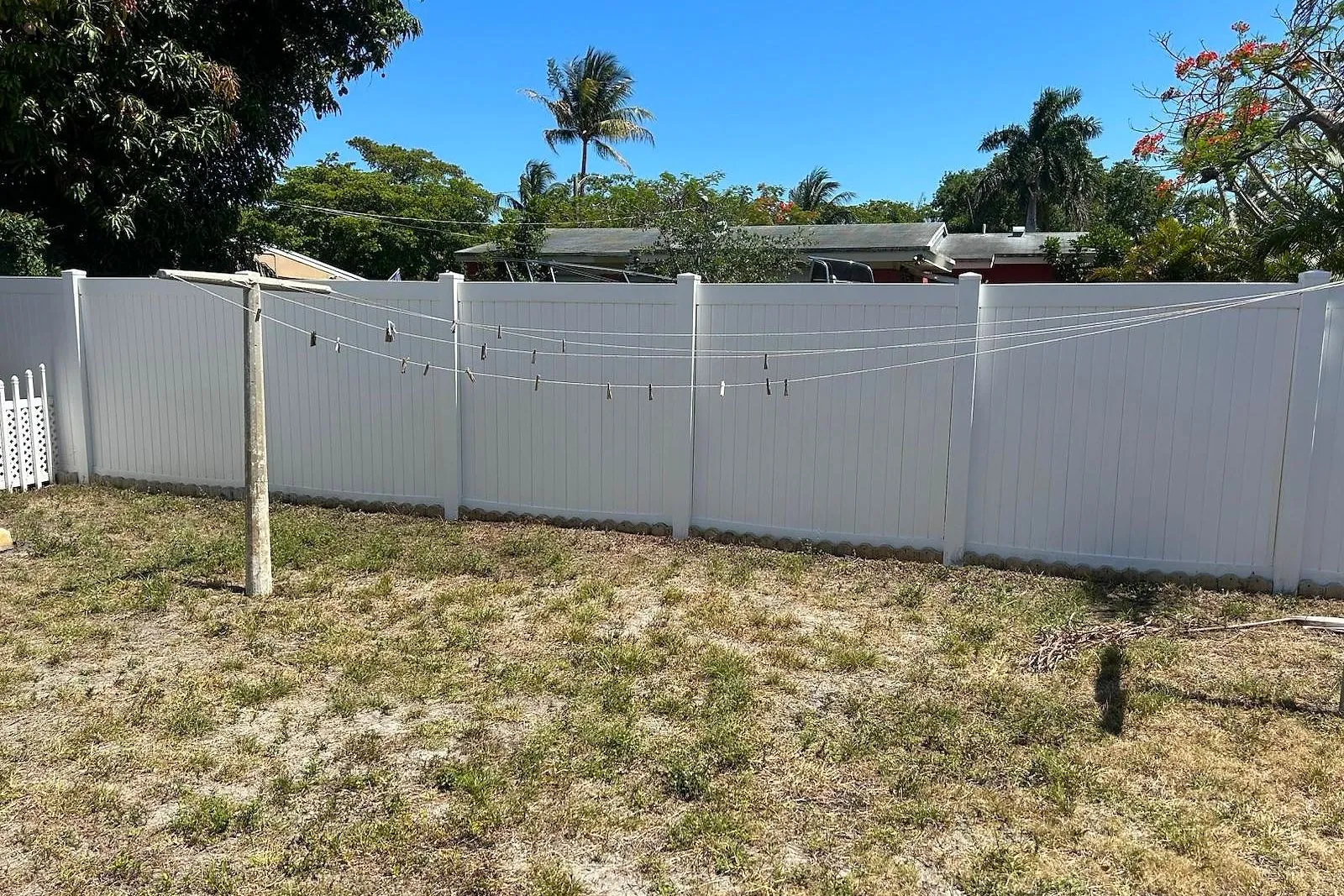 A white vinyl fence stained orange with sprinkler rust, before and after treatment — after