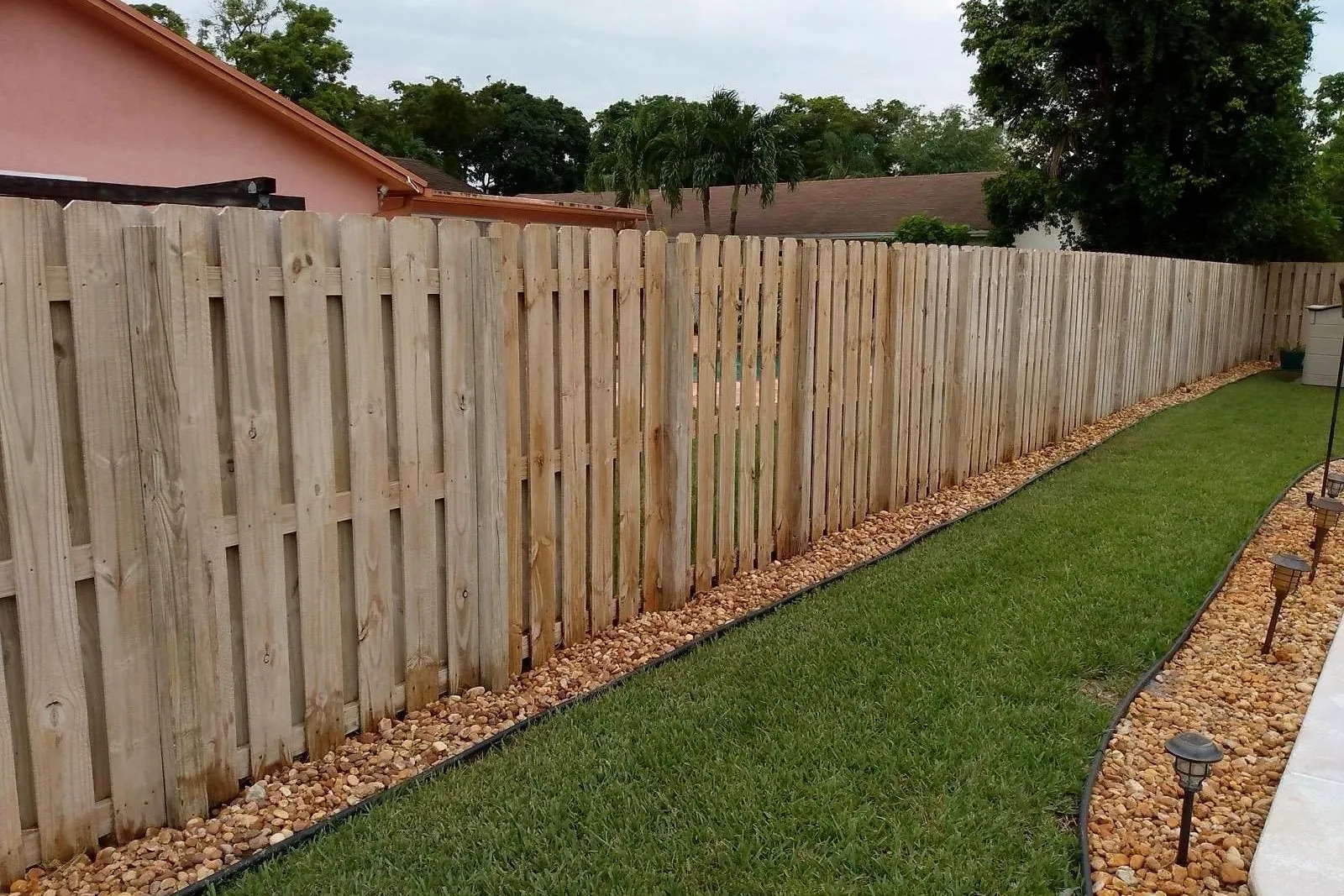 A wood fence black with mildew before and after cleaning — after