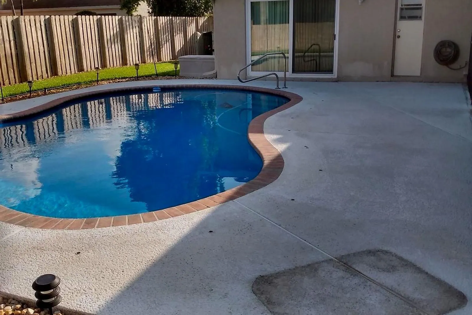 A plain concrete pool deck before and after being cleaned and coated — before