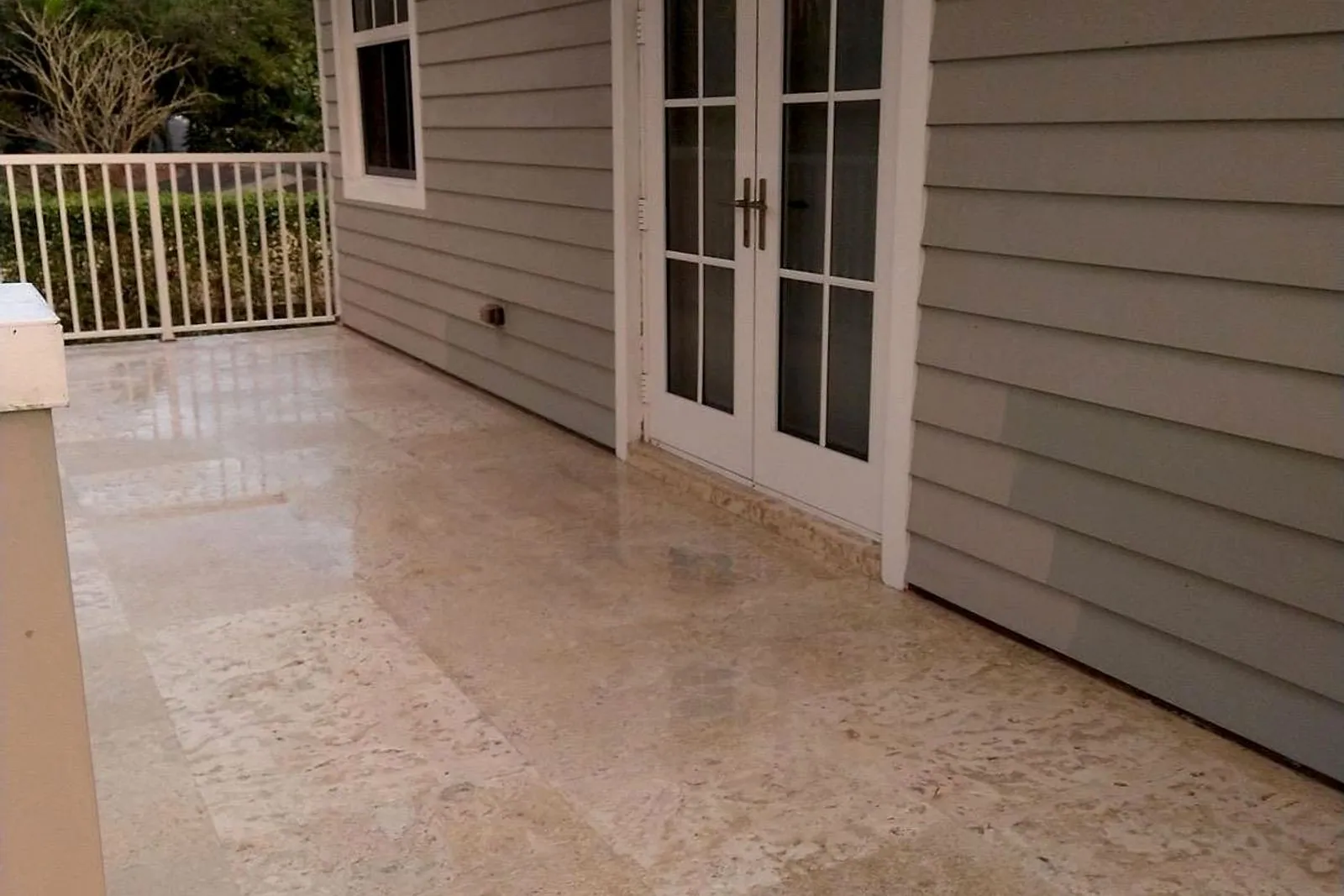 A travertine terrace beside a house, thick with algae and moss before cleaning and back to bare stone after — after