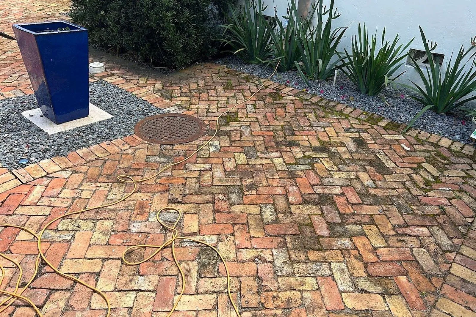 A brick paver walkway before and after cleaning — before