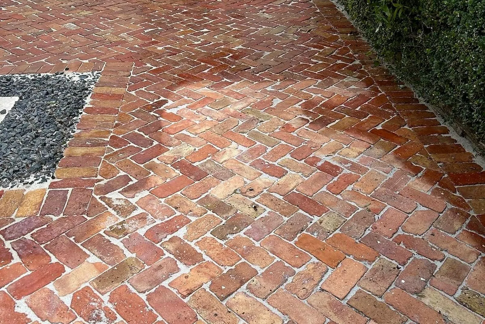 A brick paver courtyard before and after cleaning, re-sanding and sealing — before