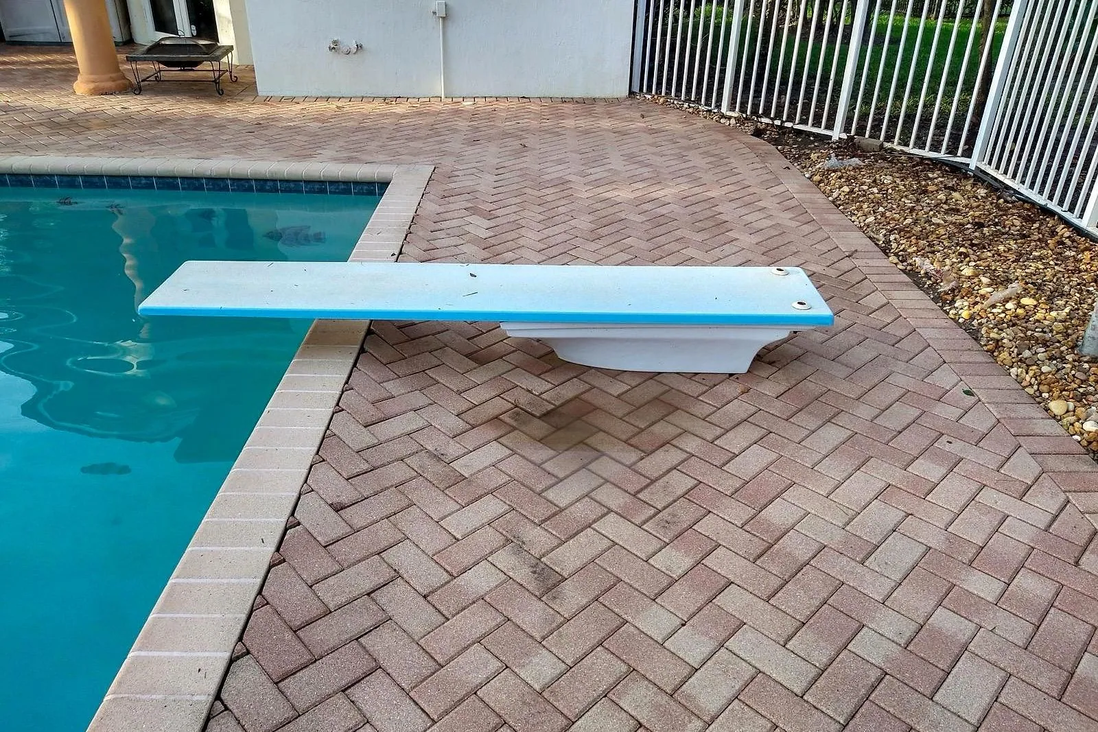 A paver pool deck with a diving board before and after cleaning — after