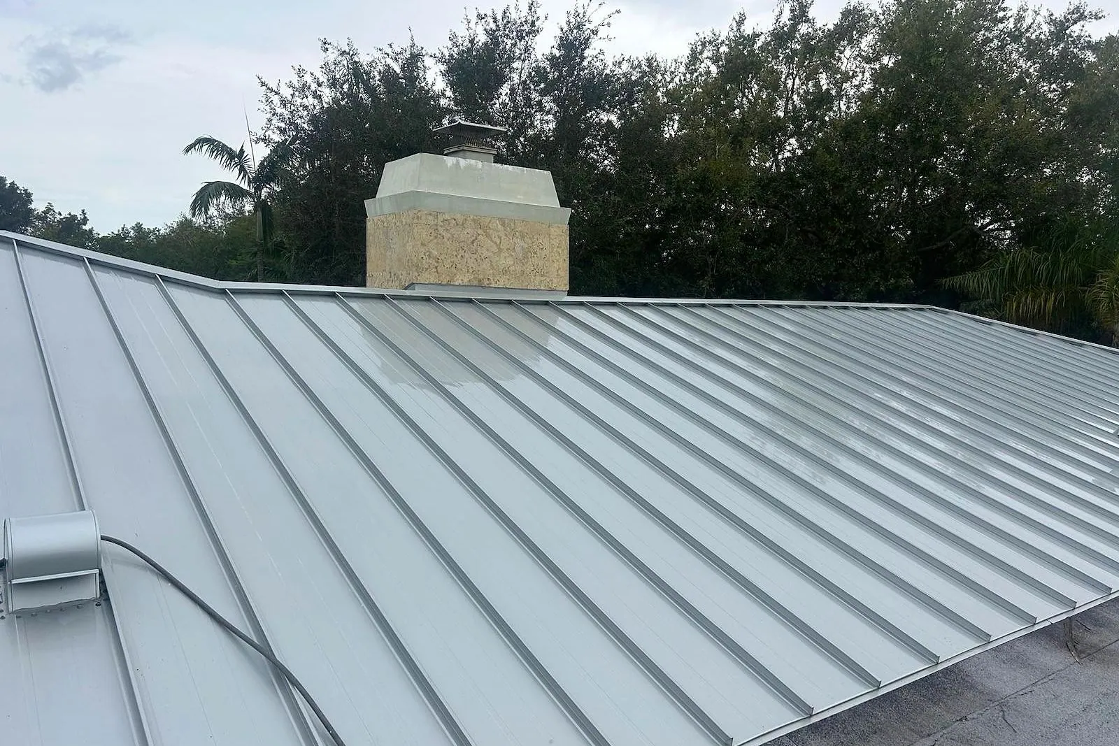 A standing seam metal roof and chimney before and after cleaning — after